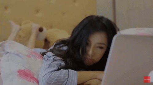 a woman laying in bed with her laptop on the side