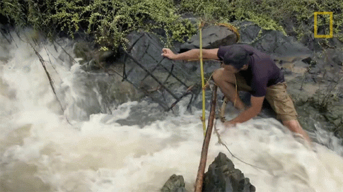 a man is trying to climb up a roped in raft