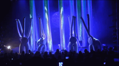 several rabbits perform on stage with bright red lighting behind them