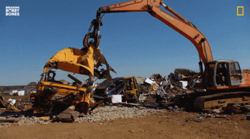 a large blue and white excavator next to a pile of rubble