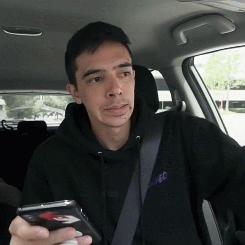 man in a car holding a cell phone and watching his video