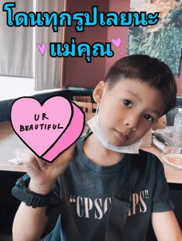 a boy holding a pink heart with an inscription on it