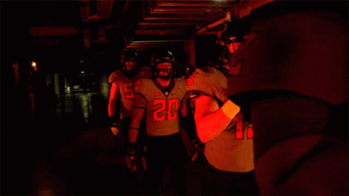 two men in uniforms are walking down a dark hallway