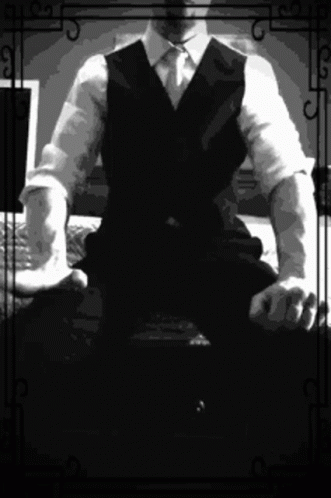 a man in a vest and tie sitting down