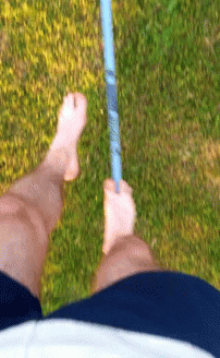 an aerial view of a person's legs on a grass field, with a stick sticking out