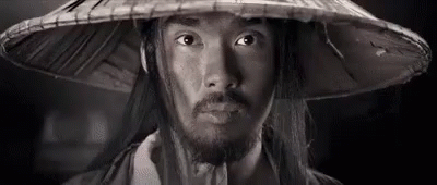 a man in a traditional chinese hat looks at the camera