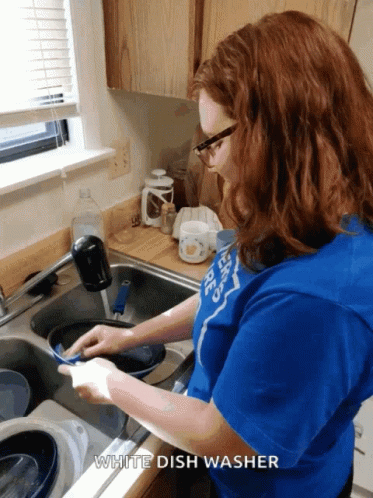 a woman is washing dishes in a sink