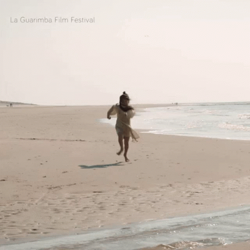 a woman running on the beach with her dog