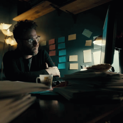 a man sitting at his desk in the dark