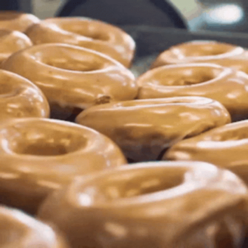 glazed donuts on a conveyor belt being transported