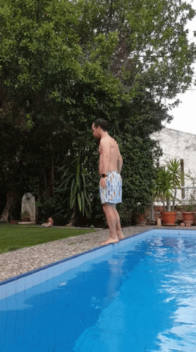 a man is swimming in a pool while a dog sits on the side