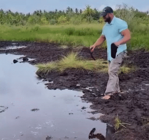 a person is digging soil by a small pond