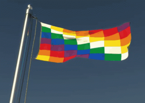 a multi colored flag flies high in the sky