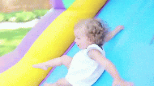 a baby on an inflatable slide in a child's playroom