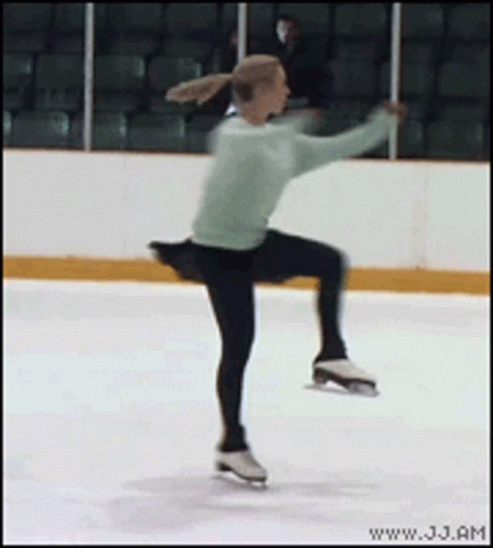 a male figure skating on a ice rink in a green shirt