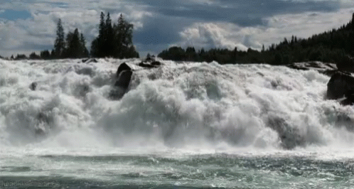 the man is surfing through the water in the river