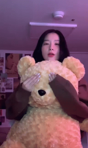 an asian girl holds a giant stuffed teddy bear