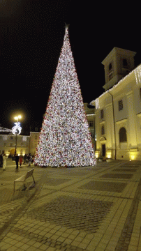 the city square has a tall white christmas tree in it