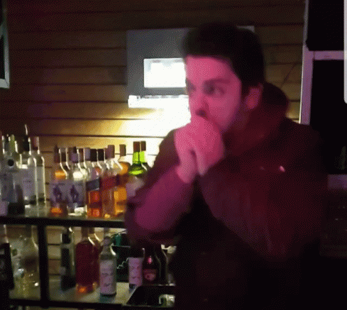 a man standing behind a bar filled with liquor bottles