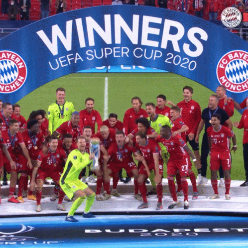 a soccer team pose on a field with their trophy