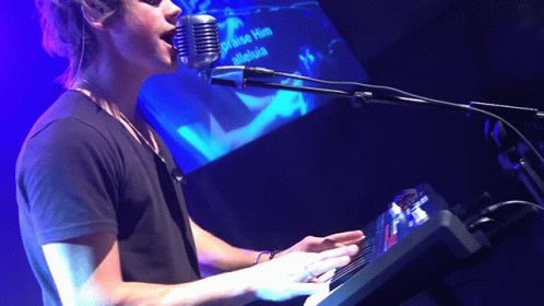 a person is playing on a keyboard at a microphone
