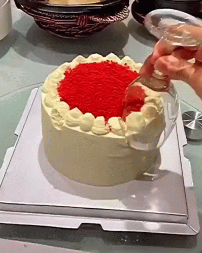 someone decorating a blue cake with white frosting