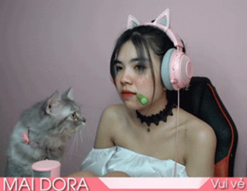 a  with makeup and headphones sitting on a couch next to a cat