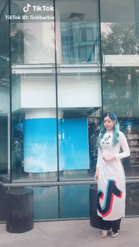 a woman in costume standing on the sidewalk next to a store window