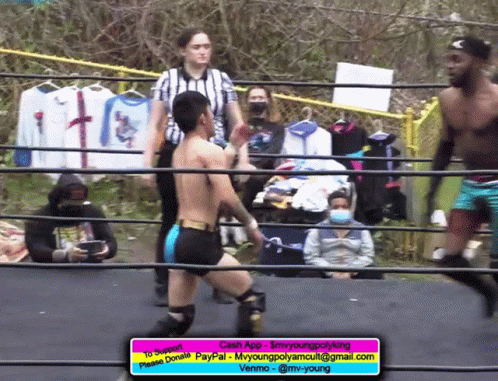 some wrestlers standing and one is holding onto a fence