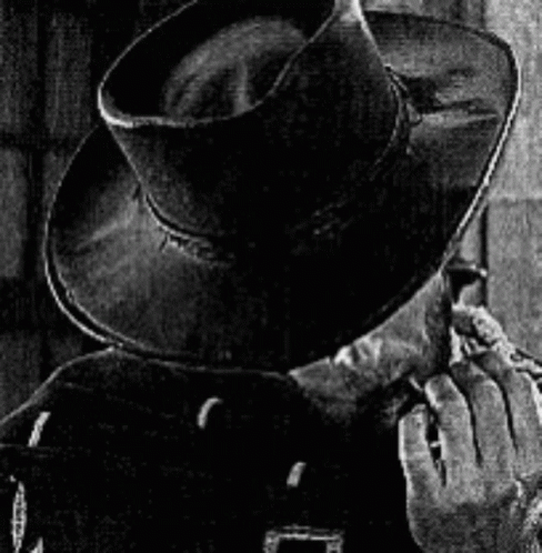 a man with his hands to his face wearing a cowboy hat