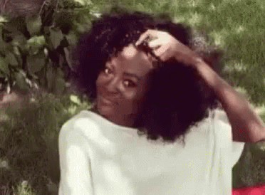 black girl sitting outside while brushing her hair
