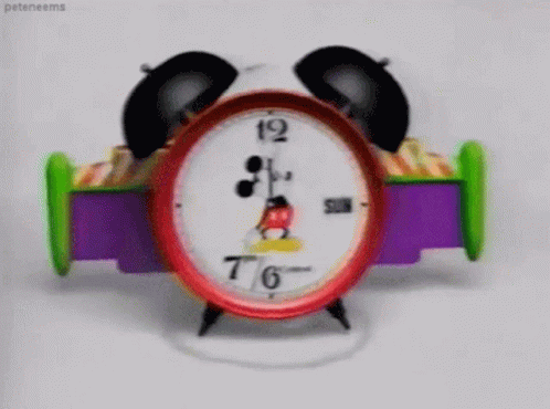 a mickey mouse toy clock is on a white surface