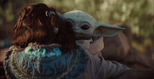a child holding an adult baby yoda doll