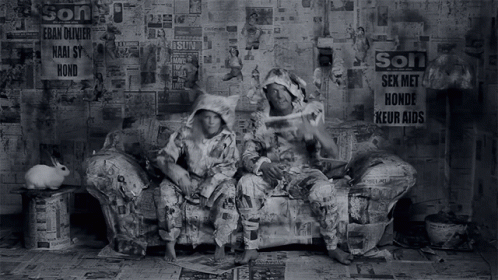 two people sitting on a chair covered in newspapers