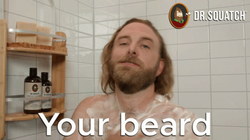 a man with a beard standing next to a shower