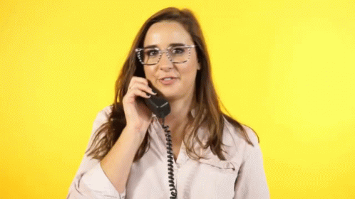 a woman wearing glasses holds a phone to her ear