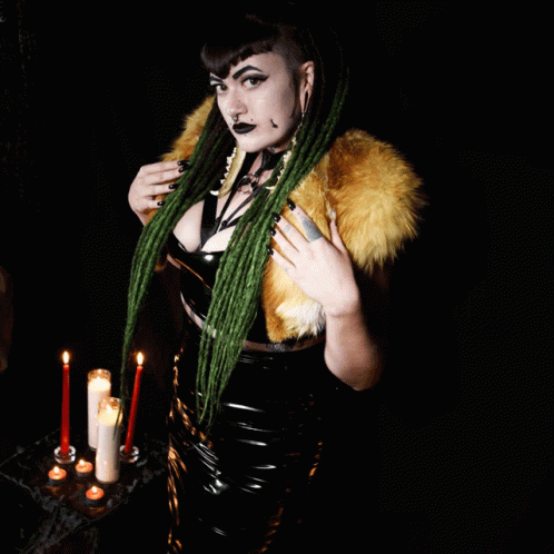 a woman dressed in latex and holding a candle with two candles