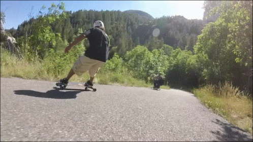 a skateboarder rides down the road near a grassy hill
