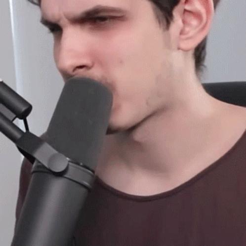 a young man with grey facial hair uses a microphone