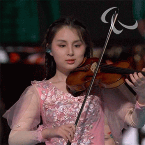 a female violinist is wearing a long pink dress and holding a violin