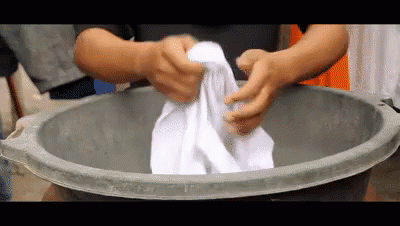 two hands using scrub cloth in a large metal bucket