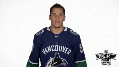 a man with blue paint on his face standing in front of an vancouver hockey team jersey