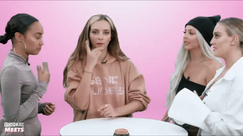 three woman wearing hoodies are talking with each other