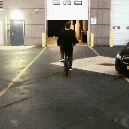 man in black jacket riding his bicycle through a garage