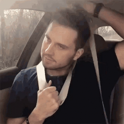 a man sitting in a car adjusting his tie