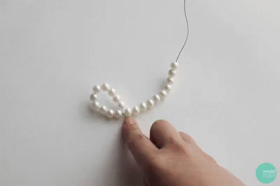 a person with a white bead necklace on their finger