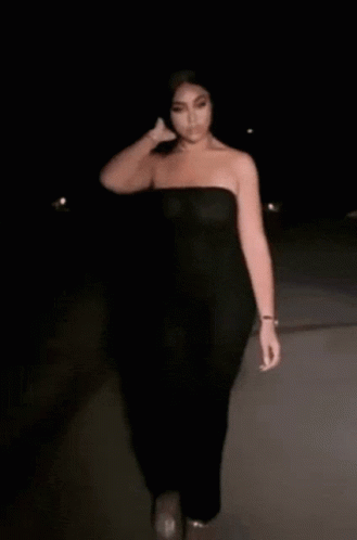 a woman walking in the dark with an over sized black dress on