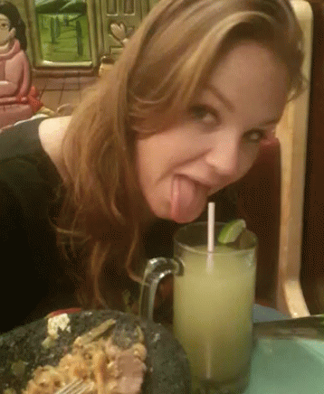 a woman sticking her tongue out while licking the side of her chocolate cake