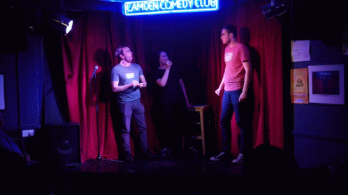 three people on stage at the comedy club