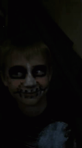 a young creepy man with glowing teeth and a skeleton makeup